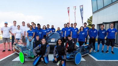 People posing in front of futuristic prototype vehicles