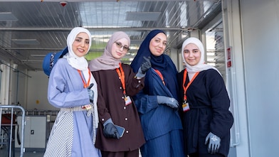 A group of women standing in front of a race paddock.