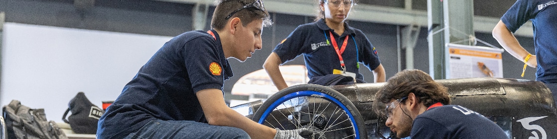 Young individuals with safety goggles and gloves working on a prototype Shell Eco-marathon vehicle