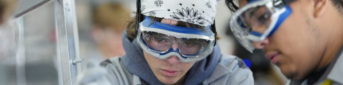 two young people wearing glasses, gloves working on a self-made car engine