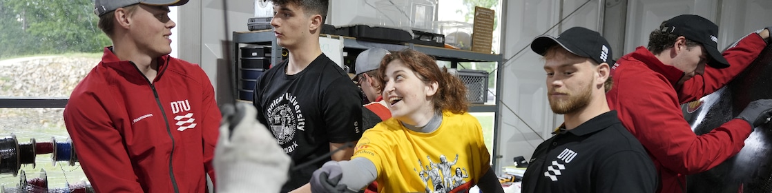 Young people in a Shell Eco-marathon event paddock, happily working on their vehicles