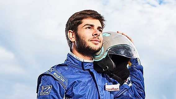 Male driver holds helmet next to car