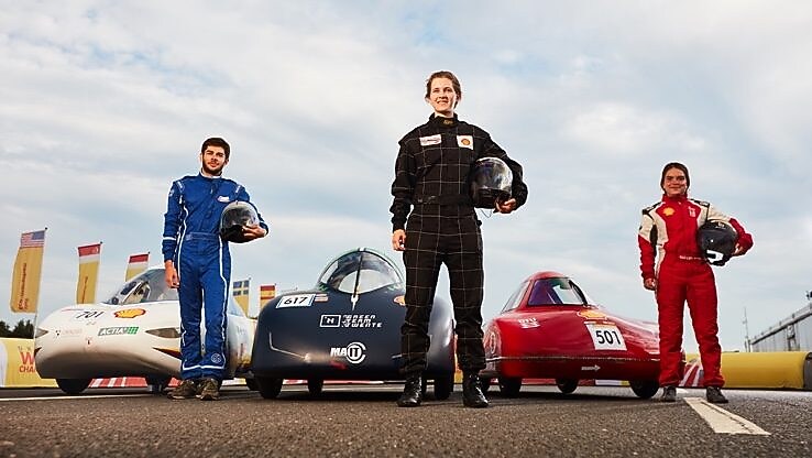 Three drivers stand in front of their vehicles