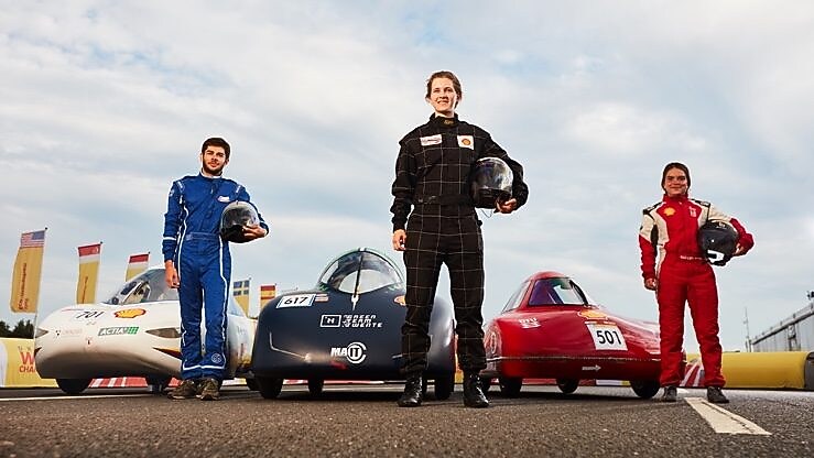 Three drivers stand in front of their vehicles
