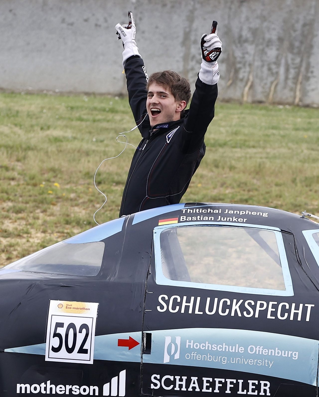 A person celebrating near a race car