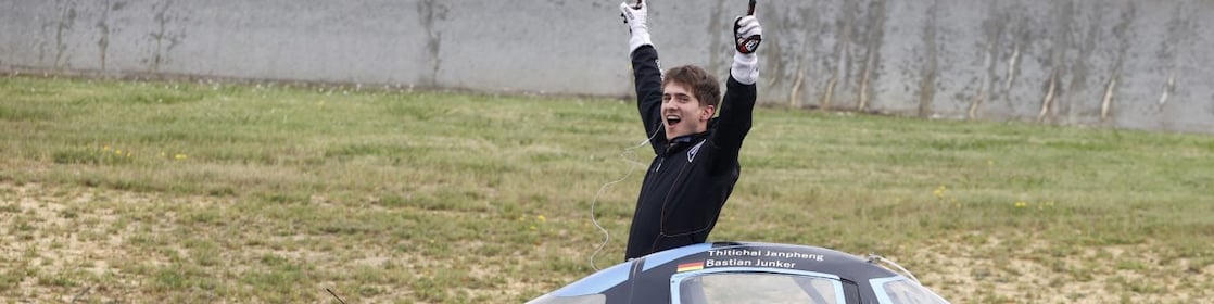 A person celebrating near a race car
