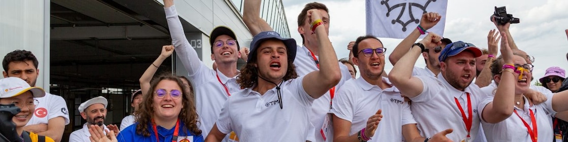 A person in a race car suit holding a helmet