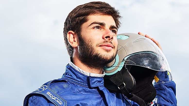 Male driver holds helmet next to car