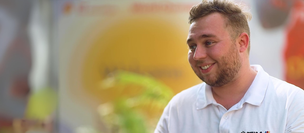a person in a white shirt looking sideways, smiling