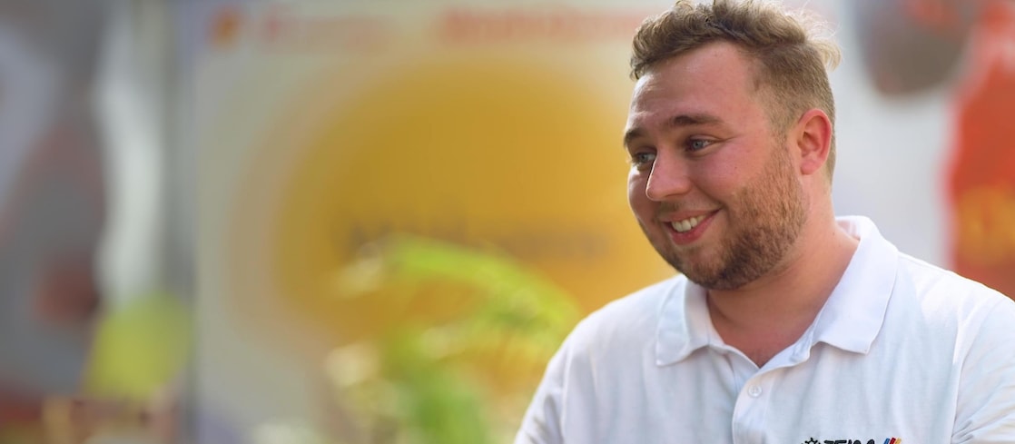 a person in a white shirt looking sideways, smiling