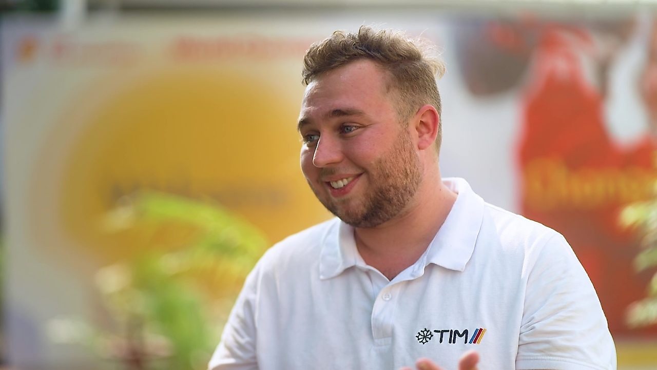 a person in a white shirt looking sideways, smiling