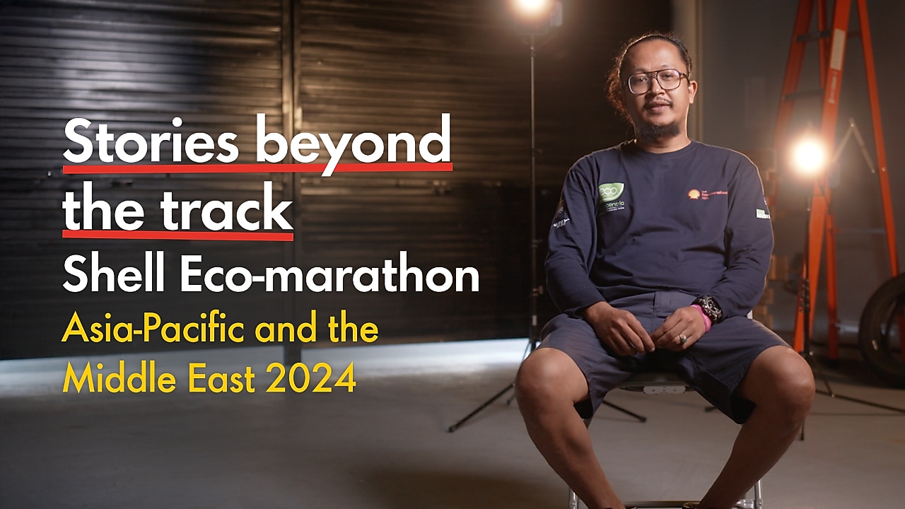 a young person seated inside a racetrack paddock, studio lights behind them