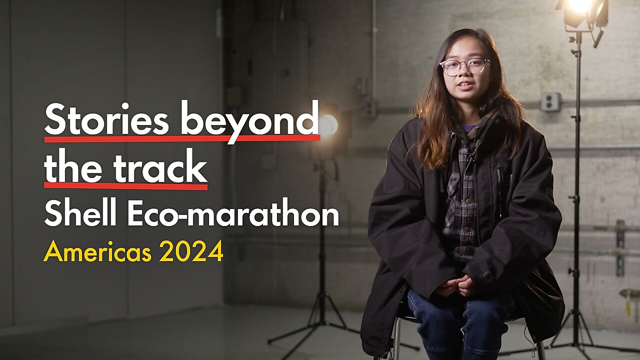Young person with glasses, talking inside a racetrack paddock