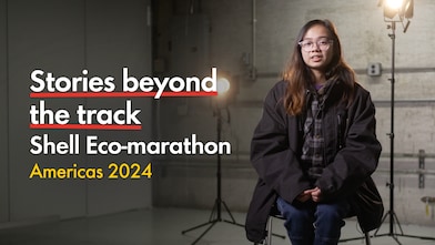 Young person with glasses, talking inside a racetrack paddock