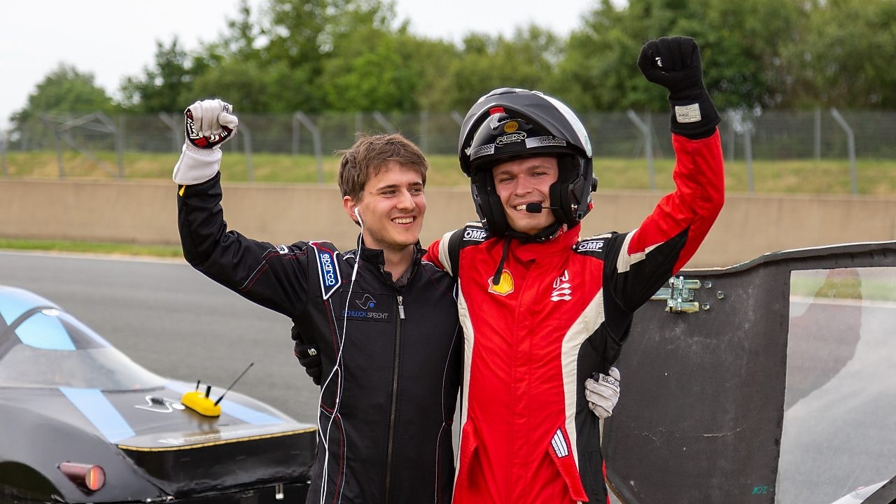 Two people in a helmet and driver's suits celebrating