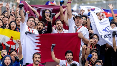 A group of young people holding the Qatar flag in a crowd