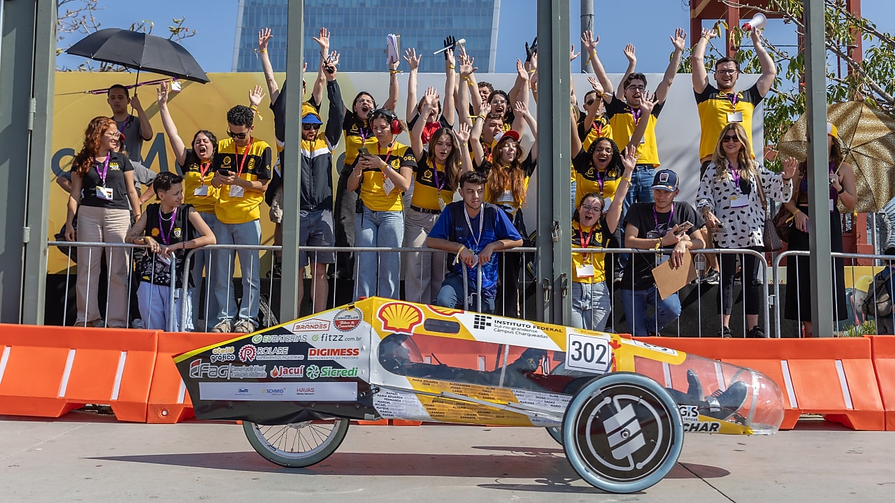 Young people cheering as a prototype vehicle passes in front of them on the track