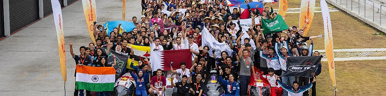 A crowd of young people holding flags, standing at a race track