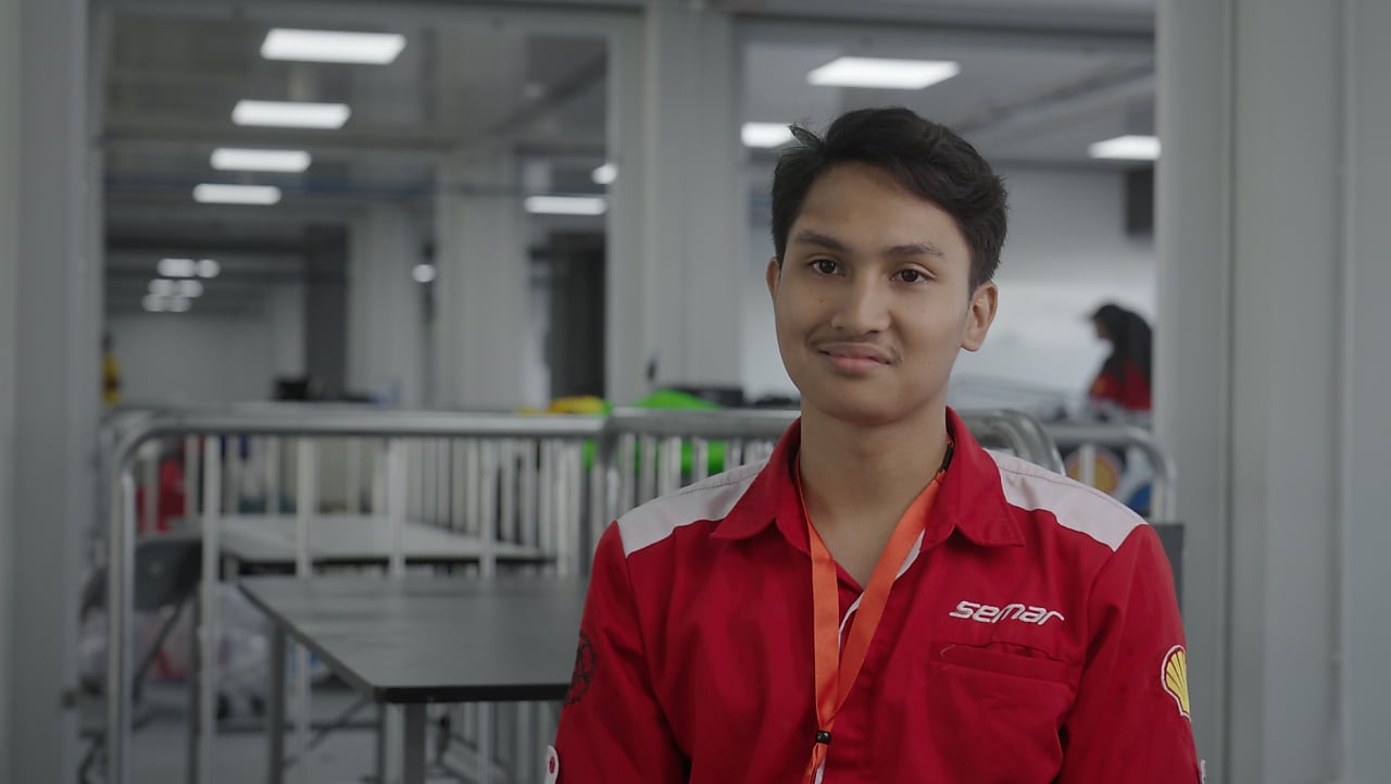 A person in red uniform inside a race paddock