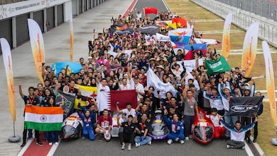 A crowd of young people holding flags, standing at a race track