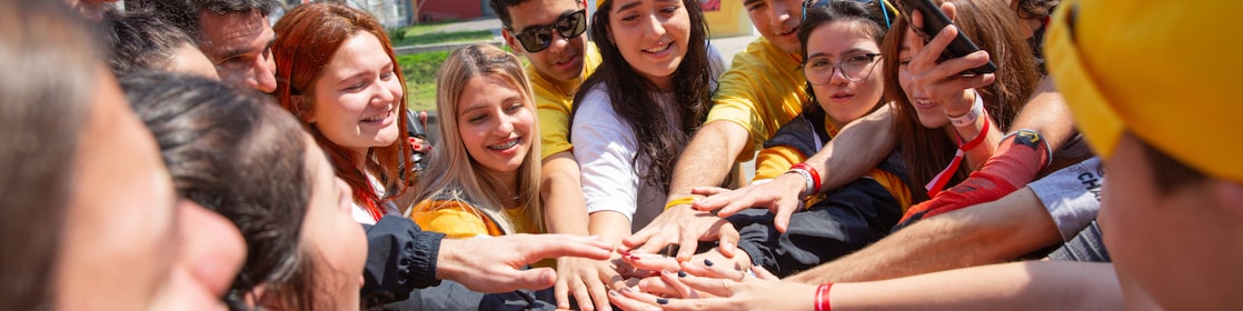  A group of young people standing in a circle with their hands piled in the middle
