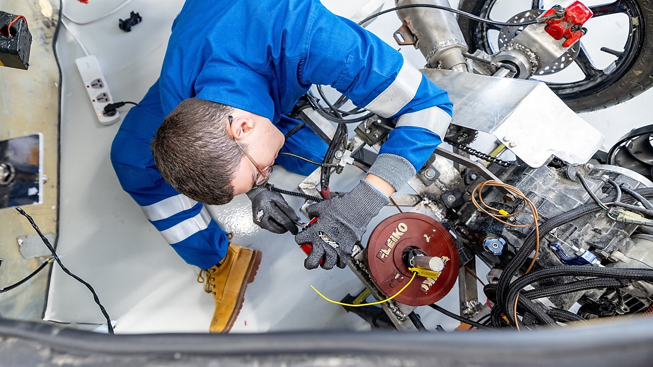 A young person working on an engine, view from the top.