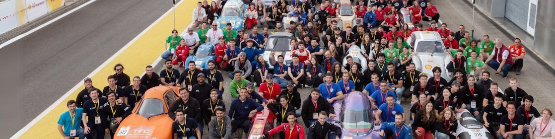 A group of people and prototype vehicles standing together at an race track