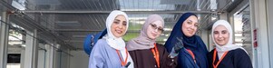 A group of women standing in front of a race paddock.