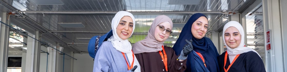 A group of women standing in front of a race paddock.