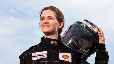 Girl holds drivers helmet on shoulder