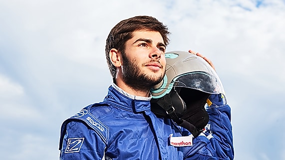 Male driver holds helmet next to car