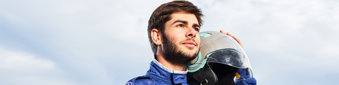 Male driver holds helmet next to car