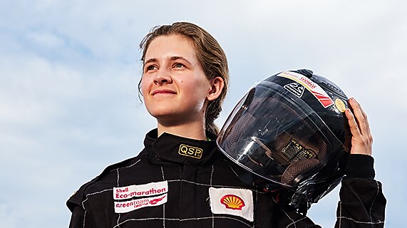 Girl holds drivers helmet on shoulder