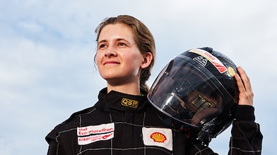 Girl holds drivers helmet on shoulder