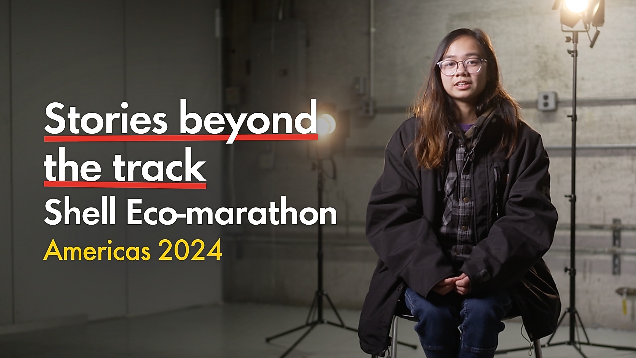 Young person with glasses, talking inside a racetrack paddock