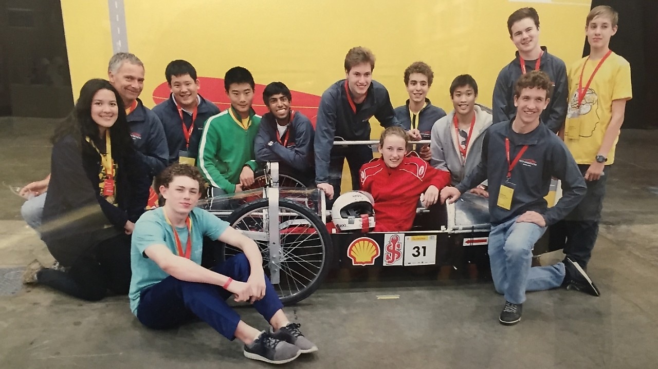 A group of young students posing in front of a self-built prototype car