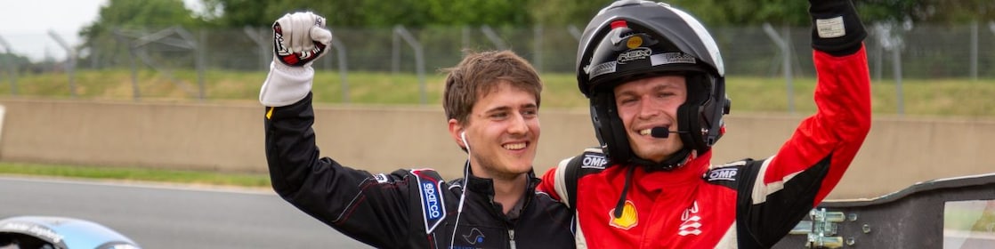 Two people in a helmet and driver's suits celebrating
