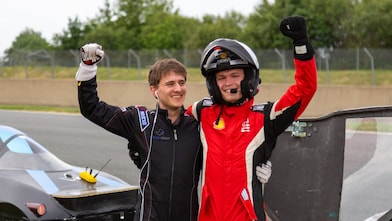 Two people in a helmet and driver's suits celebrating