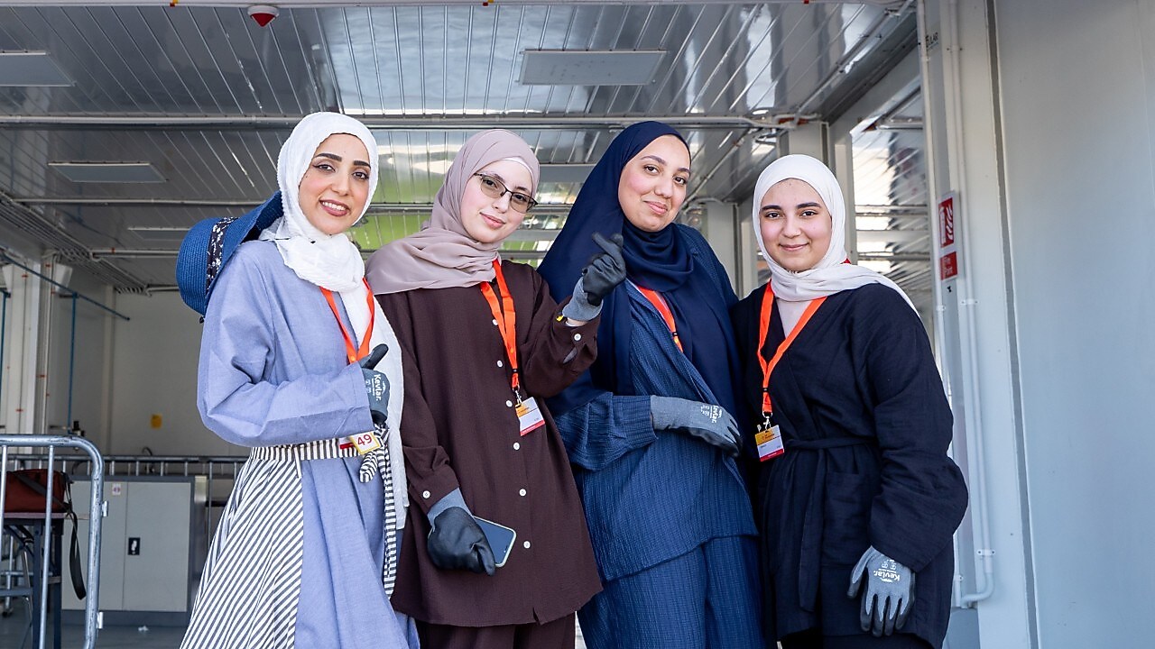 A group of women standing in front of a race paddock.